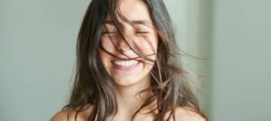 Close-up portrait of a beautiful girl smiling with her hair blowing in wind