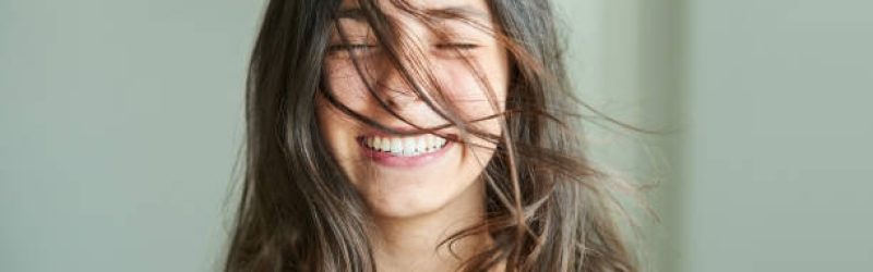 Close-up portrait of a beautiful girl smiling with her hair blowing in wind